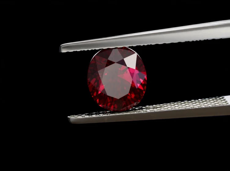 A ruby held in tweezers